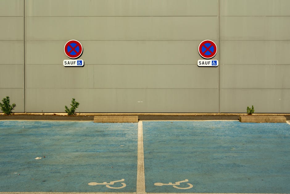 A beige exterior wall with two circular no parking signs indicating restrictions, each featuring a red border and blue background with a red diagonal line across. Below each sign, a label reads 'SAUF'
